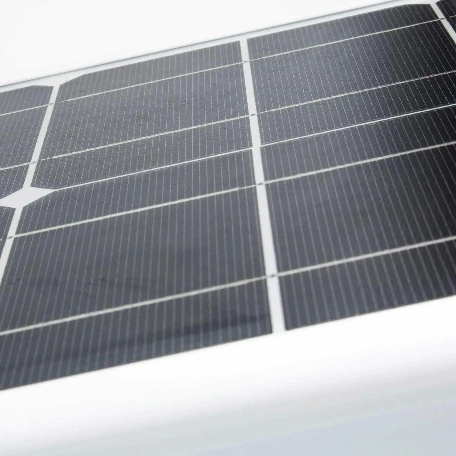Close-up of solar panel array with multiple photovoltaic cells separated by white gridlines, mounted at an angle against whit