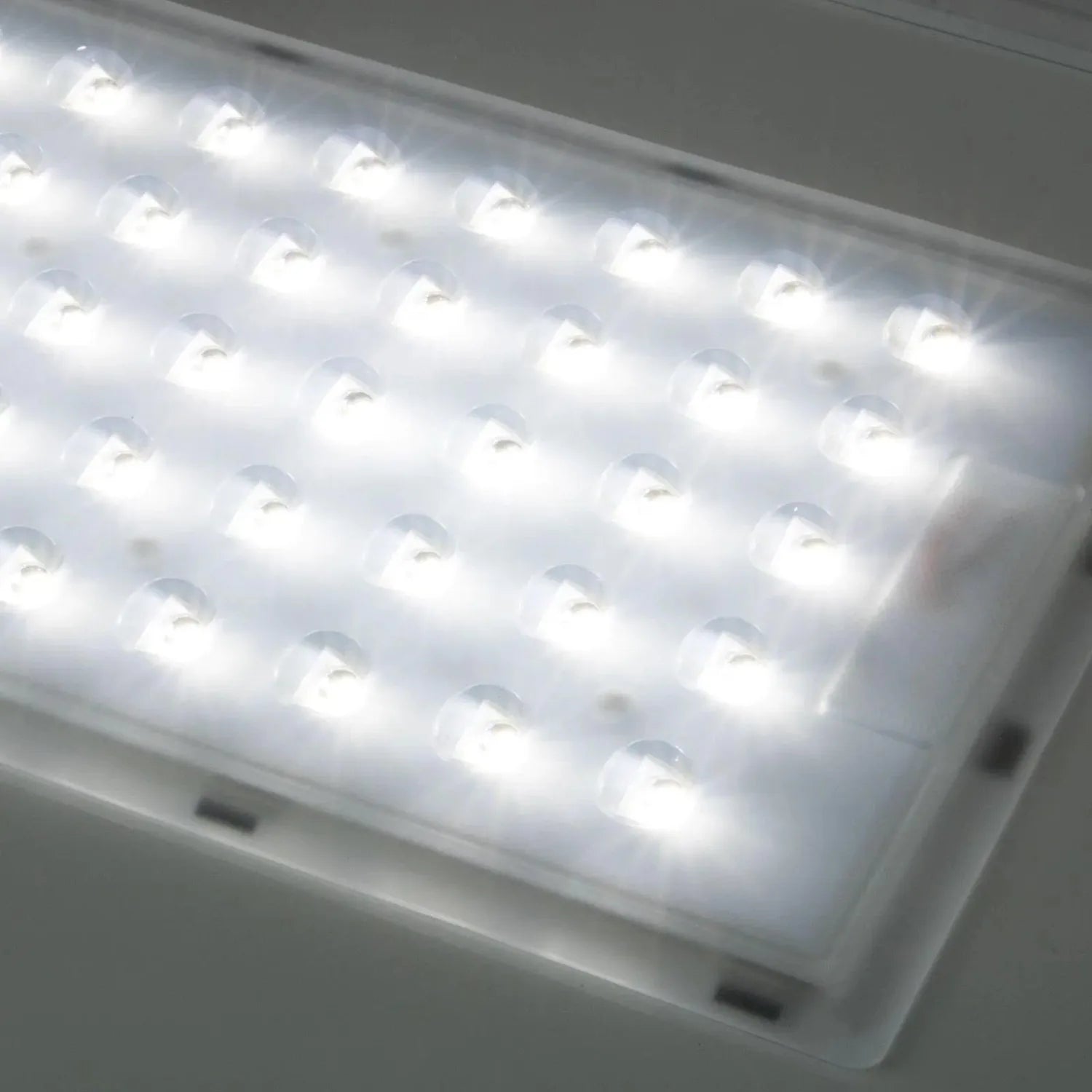 White rectangular LED panel with multiple bright light units mounted on ceiling, showing installation shot of solar street li