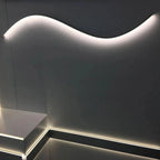 Curved white LED light fixture mounted on dark wall, showing installation example with illuminated aluminum profile and flexi
