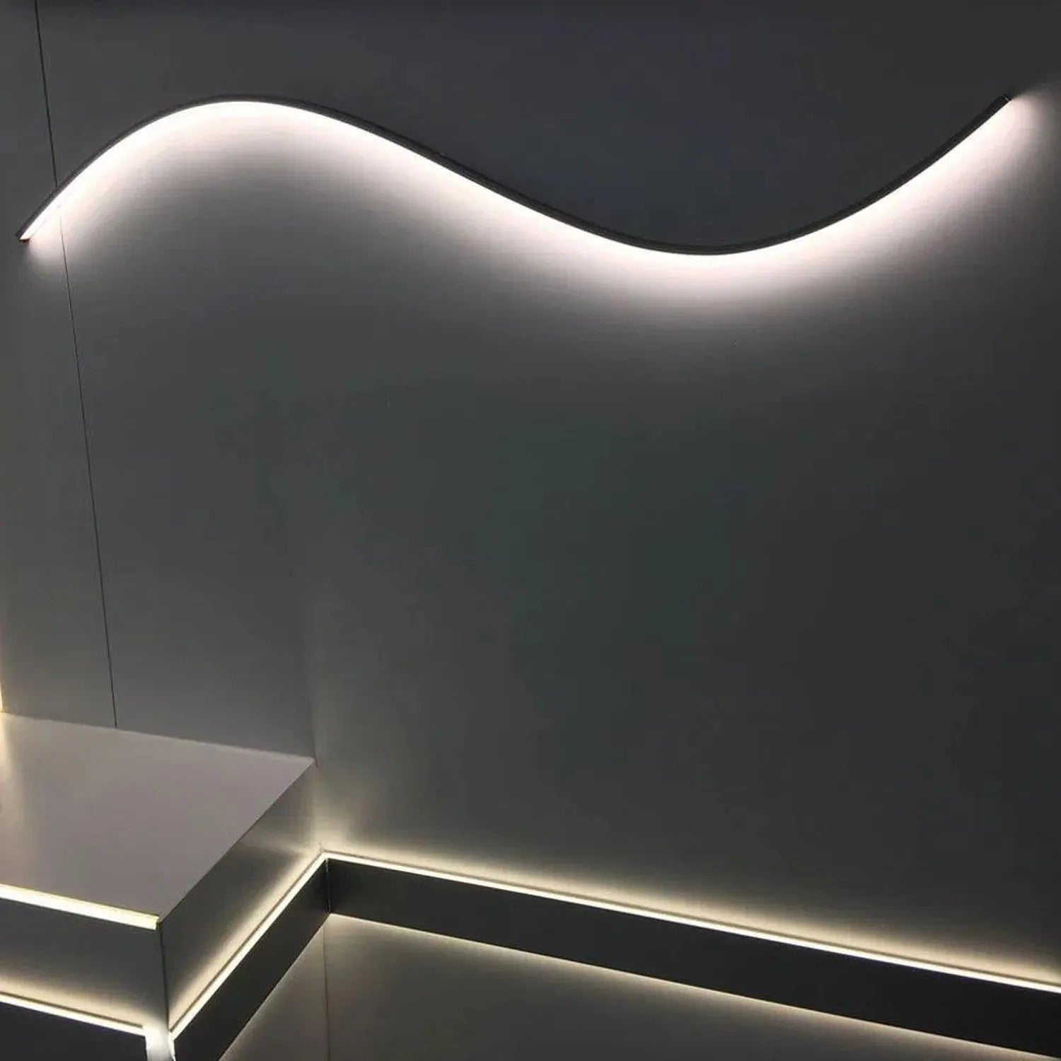 Curved white LED light fixture mounted on dark wall, showing installation example with illuminated aluminum profile and flexi