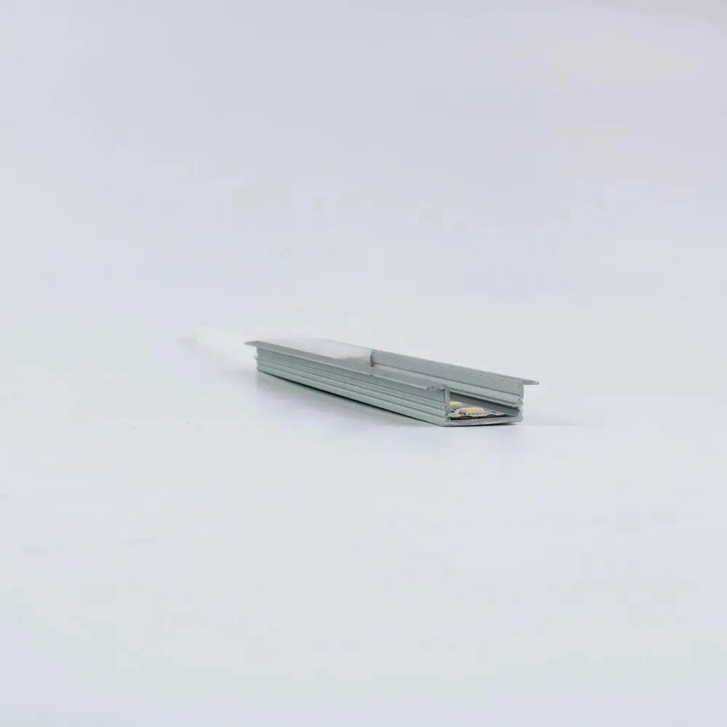 Recessed aluminum U-channel profile for LED strips, angled view showing grooved interior and flat mounting surface against wh