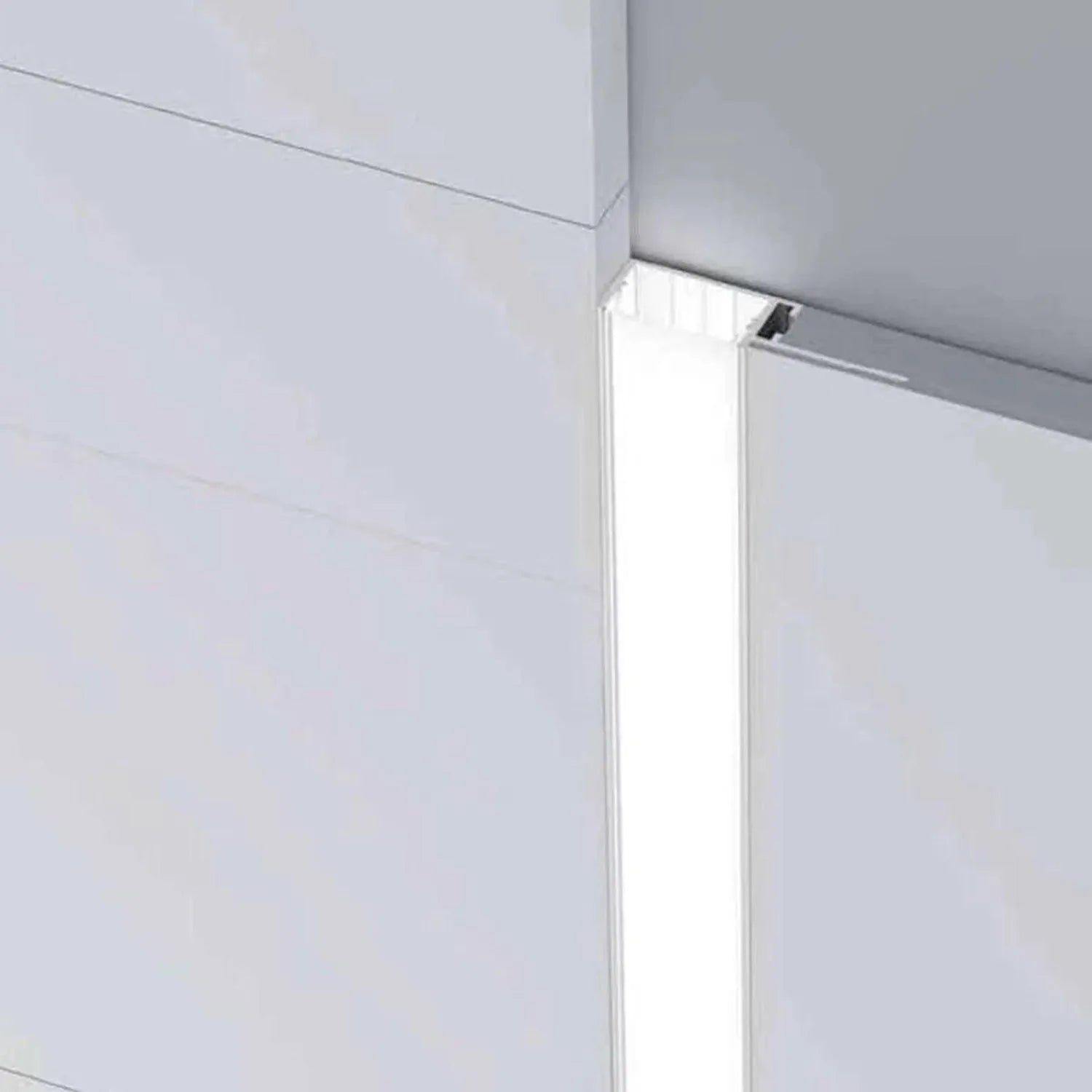 Recessed LED profile mounted vertically in drywall corner, showing white aluminum channel with integrated lighting strip.