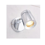 Polished chrome cylindrical LED bathroom spotlight mounted on white wall, angled downward with warm light glowing from openin