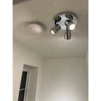 Chrome ceiling spotlight fixture with three adjustable GU10 LED spots mounted on white bathroom ceiling next to round recesse