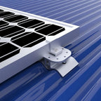 White mounting pad with bolt holes securing solar panel to blue corrugated metal roof, installation shot.
