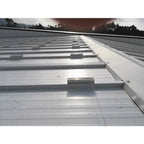 No-Drill Solar Panel Mounting Kit installed on flat metal roof with bonded rails and cable management system, forested backgr