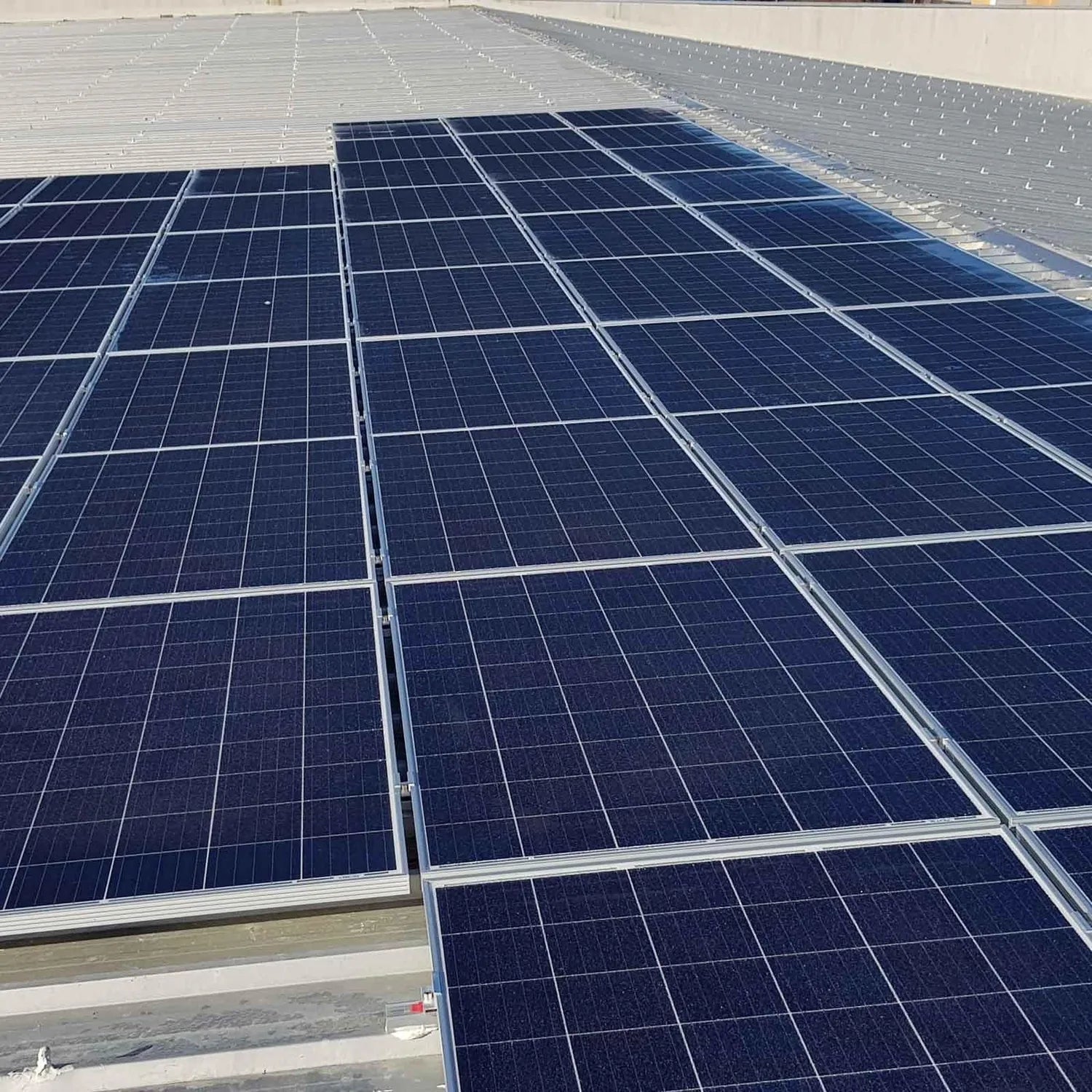 Rooftop installation of solar panels mounted with bonded rails on a flat metal roof surface.