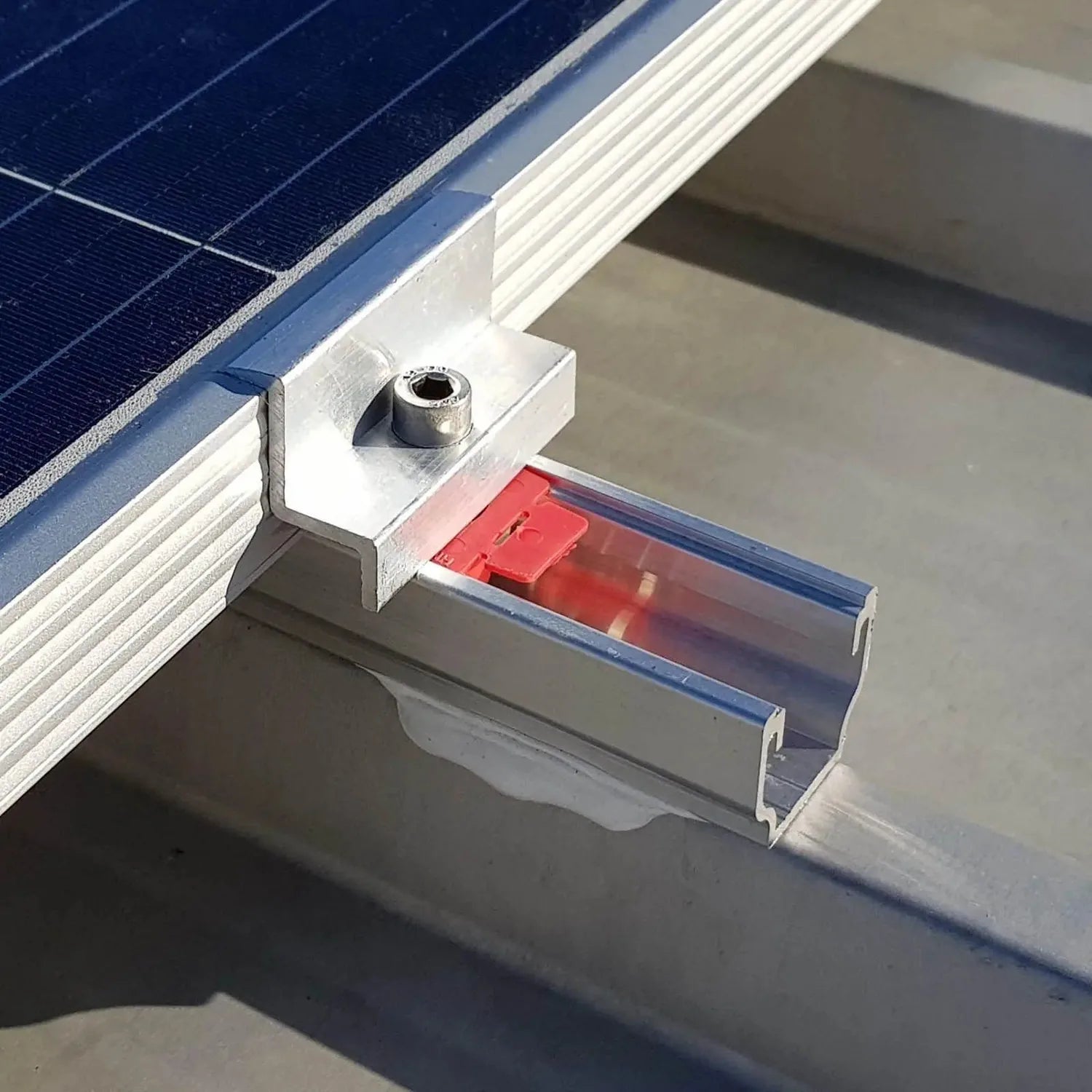 Solar panel mounting bracket installed on roof rail, showing white aluminum clip with bolt attachment and red foam base pad.