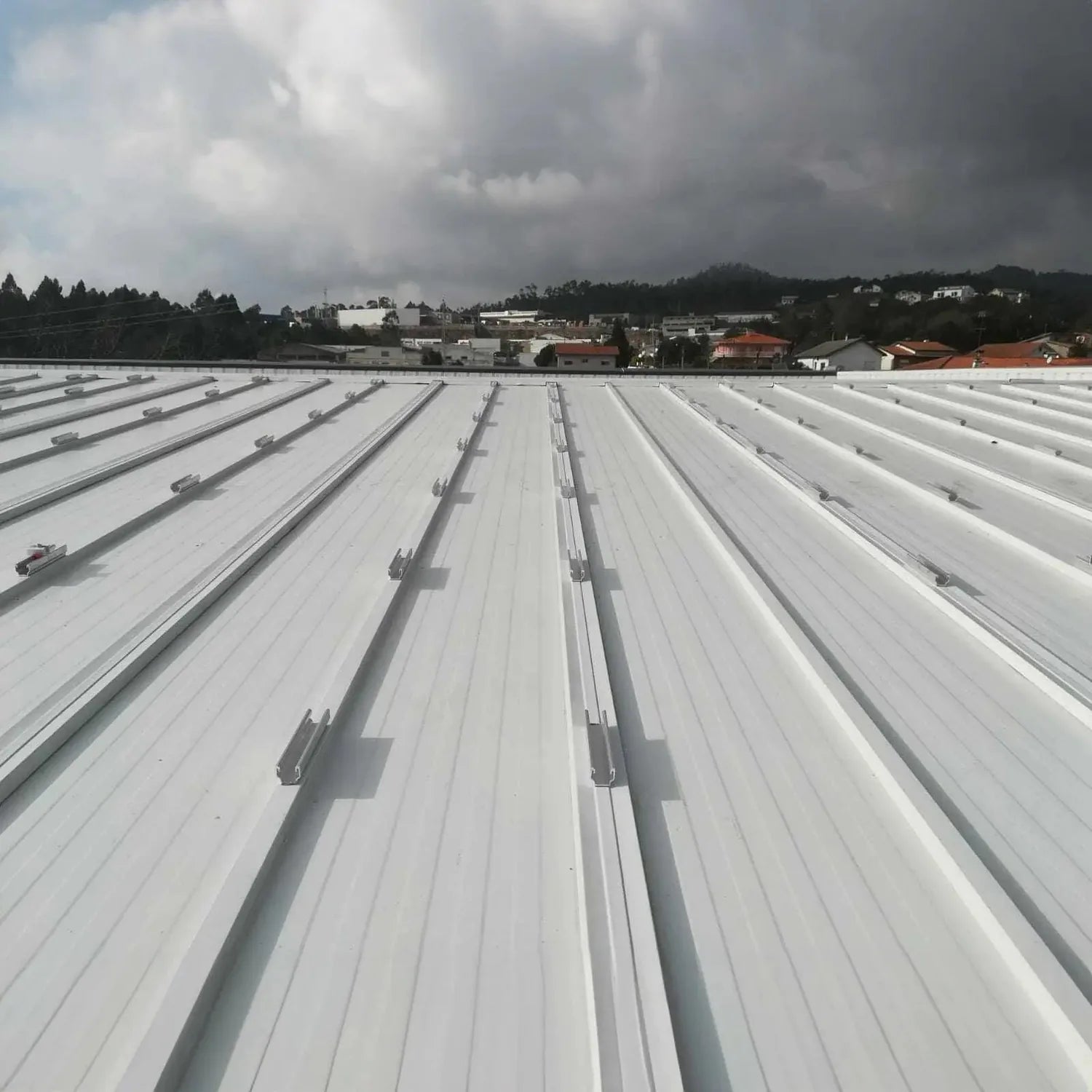 No-Drill Solar Panel Mounting Kit installed on flat metal roof with parallel rails and clamps, suburban landscape visible in 