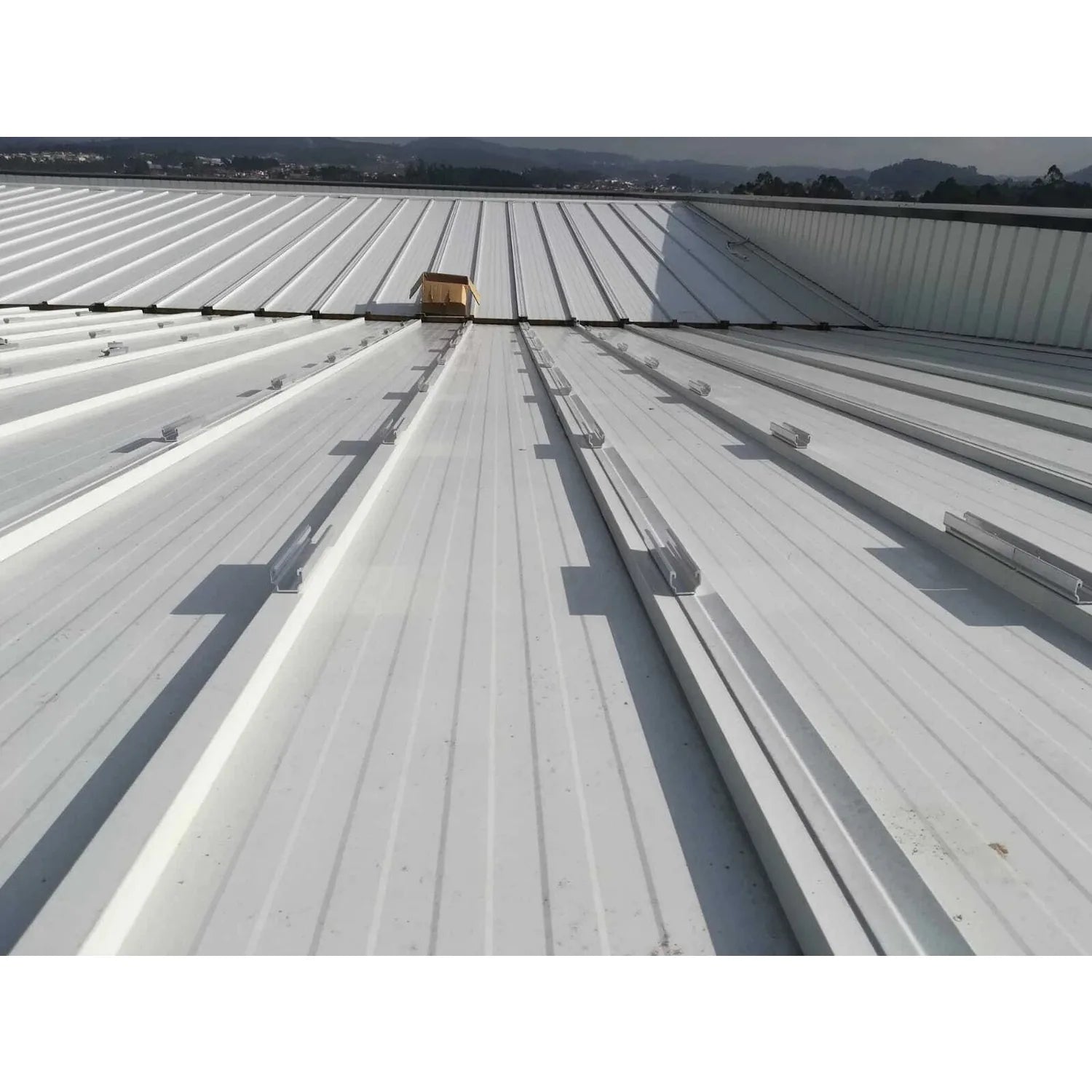 No-Drill Solar Panel Mounting Kit installed on metal roof with bonded rails running parallel across white corrugated panels, 