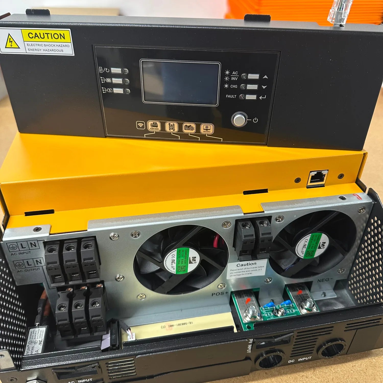 Open yellow case showing interior of 5kW solar inverter with dual cooling fans, circuit boards, and terminal connections visi