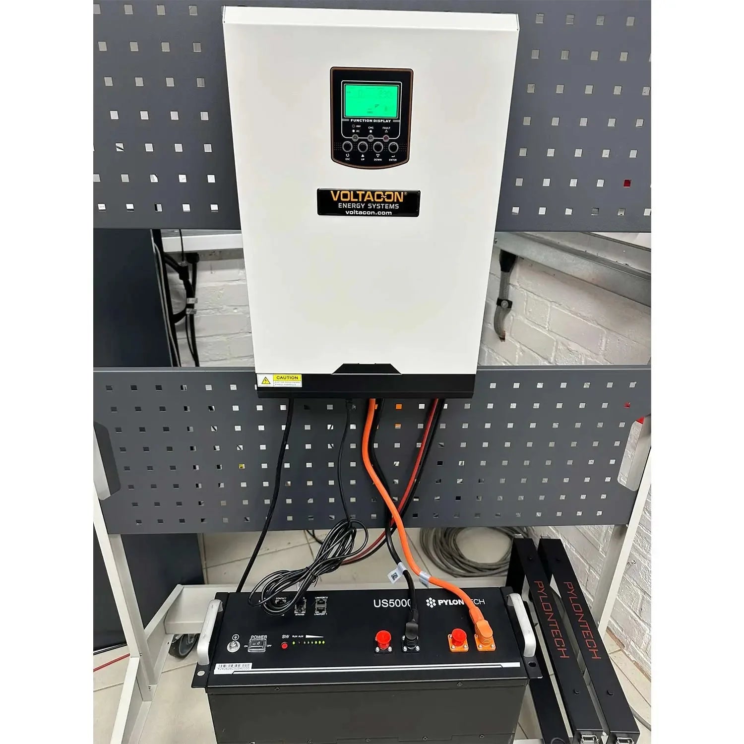 Voltacon 5kW inverter installed in white cabinet above Pylontech battery and US5000 power management system on perforated wal
