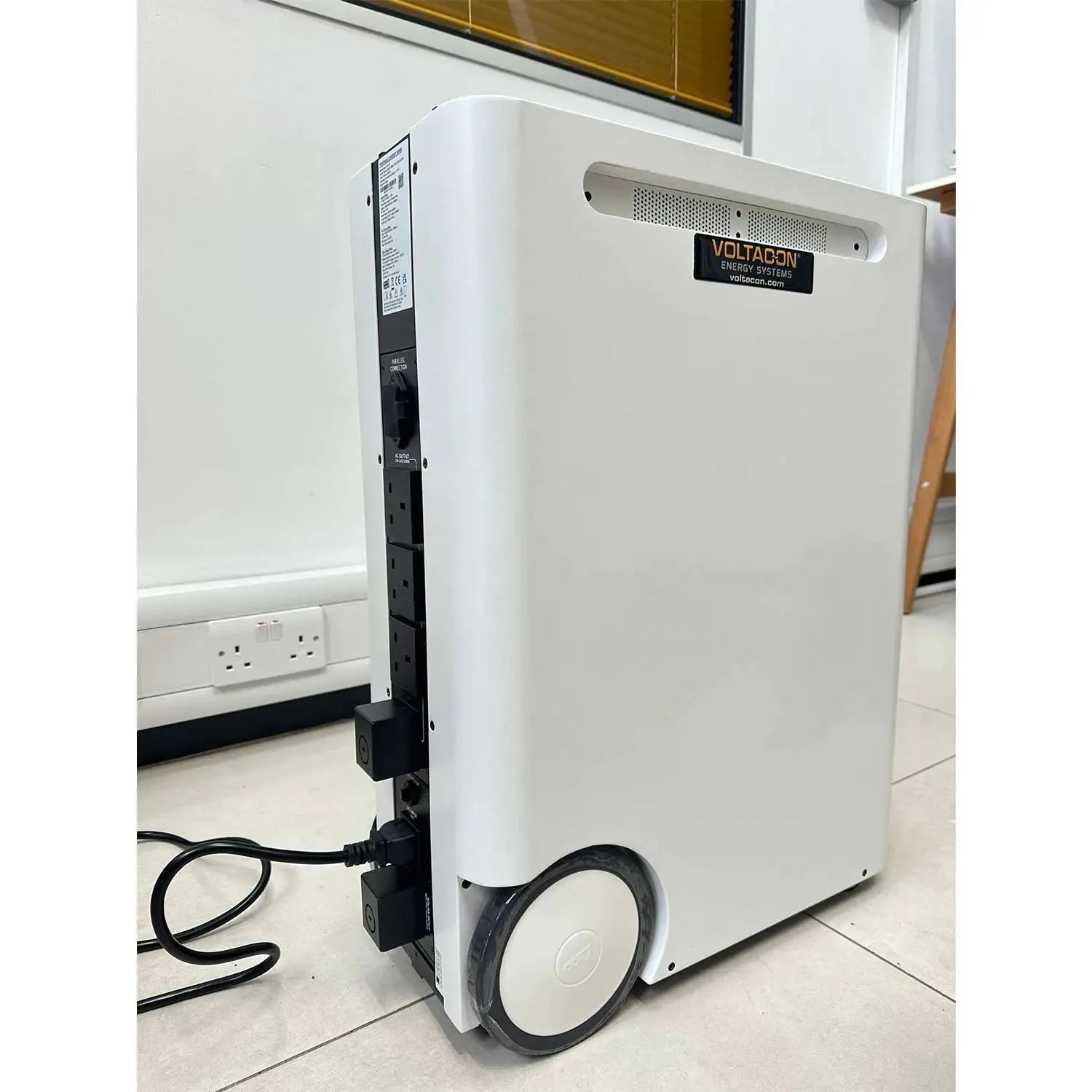 Voltacon Energy Systems portable power station with white cylindrical body and wheels, displayed in an indoor setting on tile