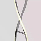 Artika Swirl Chrome LED Floor Lamp with two curved arms crossing in an X formation, one emitting warm white light, against ne