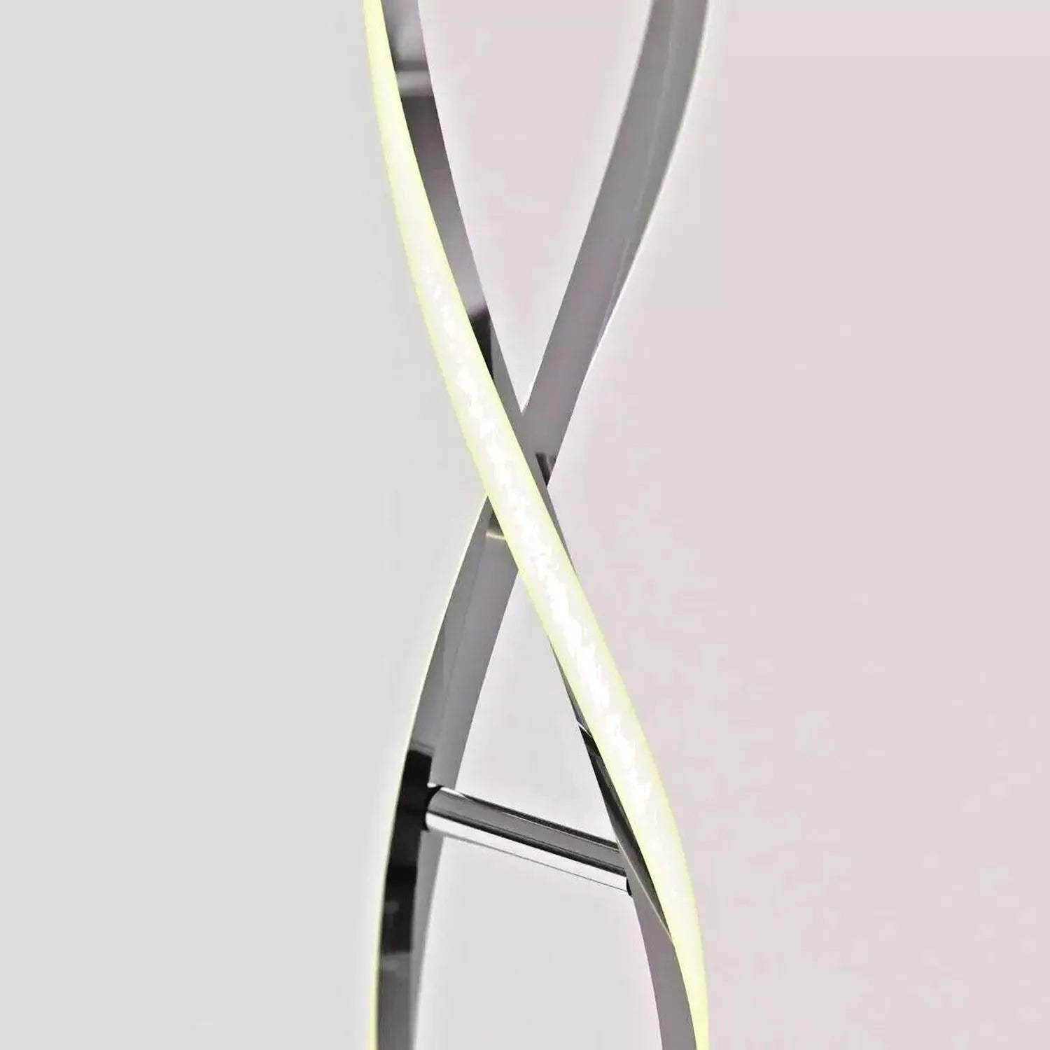 Artika Swirl Chrome LED Floor Lamp with two curved arms crossing in an X formation, one emitting warm white light, against ne