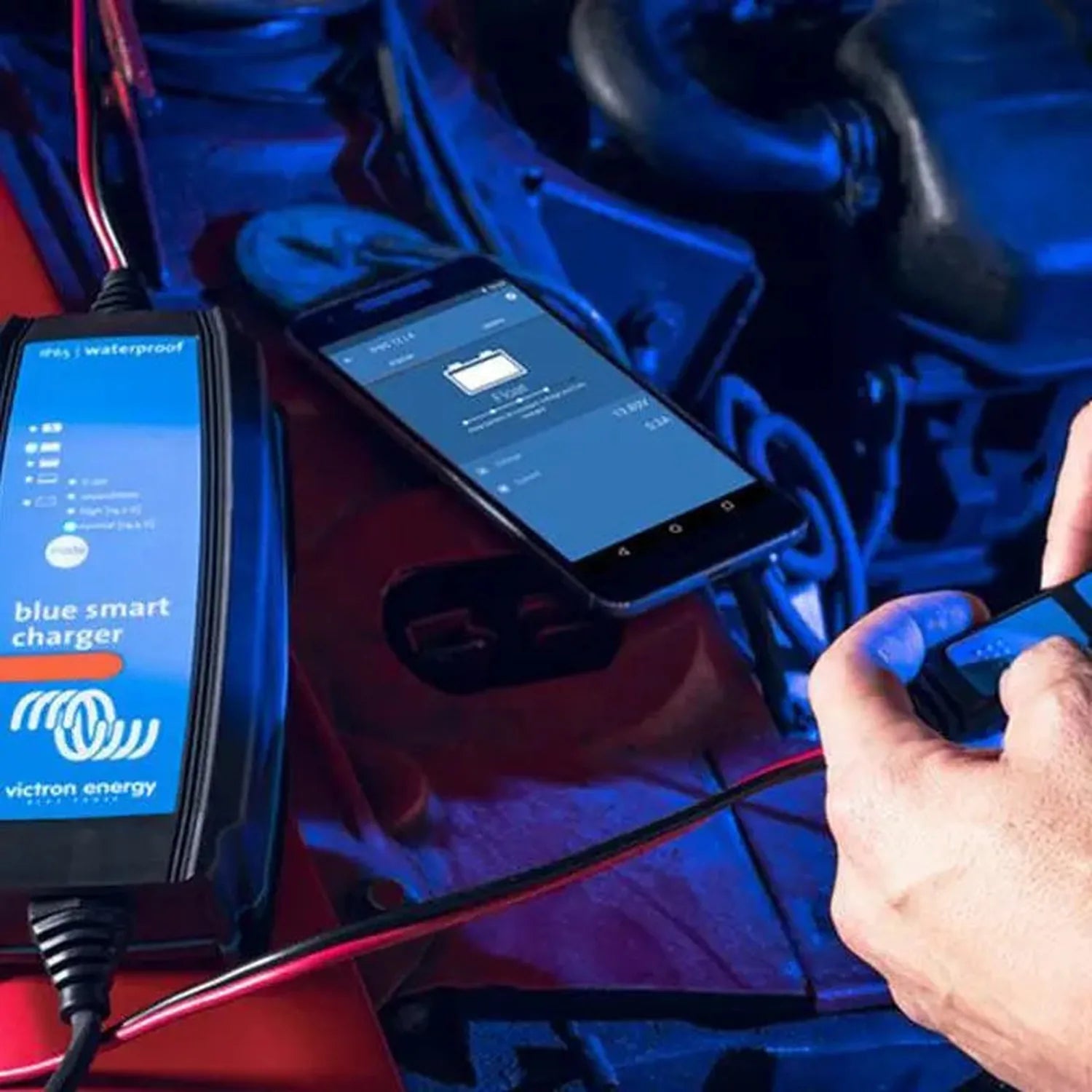 Victron Blue Smart charger with waterproof IP65 rating connected to smartphone displaying charging app, mounted on red and bl