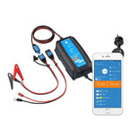 Victron Blue Smart battery charger with cables, clamps, and smartphone app display showing 13.8V output and 10.0A current.