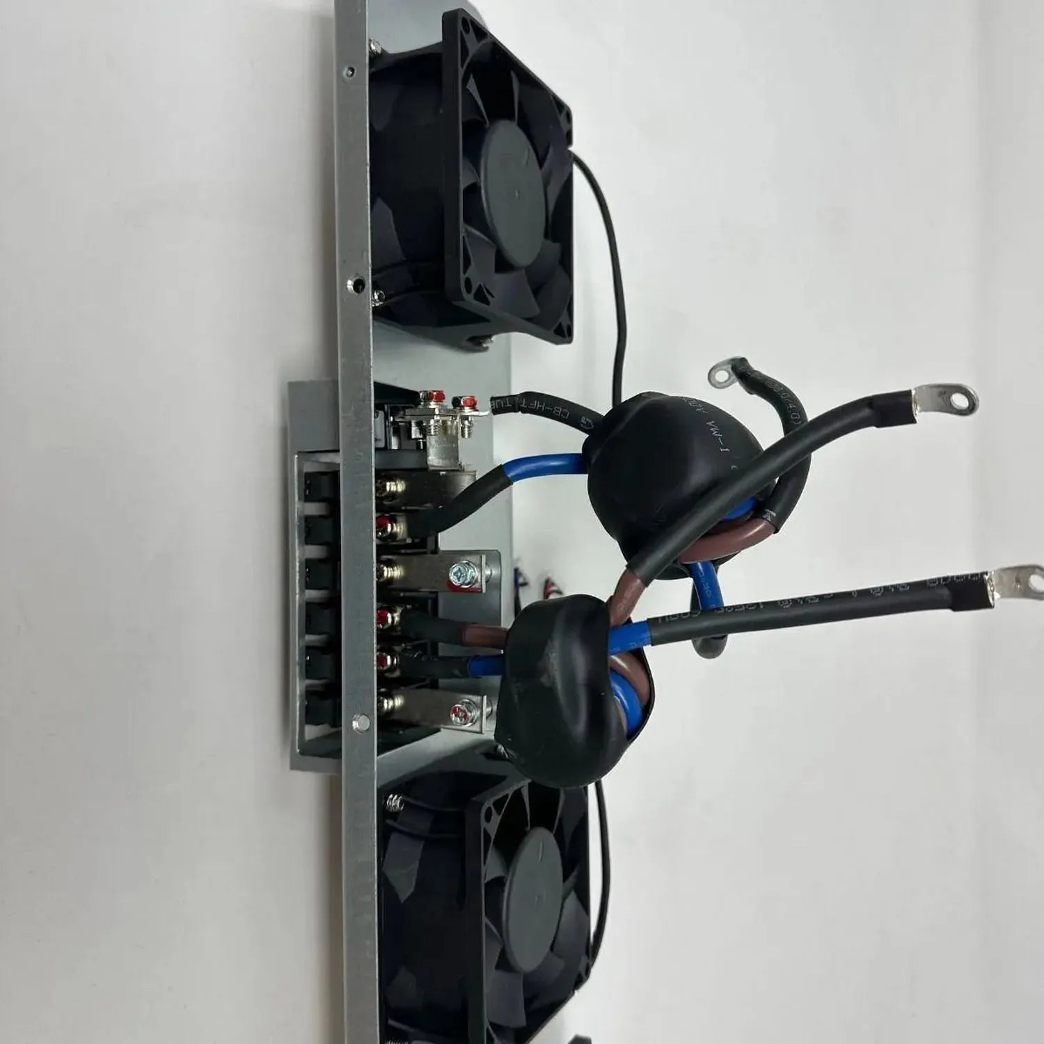 Cooling fan assembly mounted on vertical metal frame with dual black axial fans, blue wiring harness, and circuit board with 