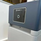 Pylontech Force controller mounted on white base, displaying zero on touchscreen display in industrial warehouse setting.