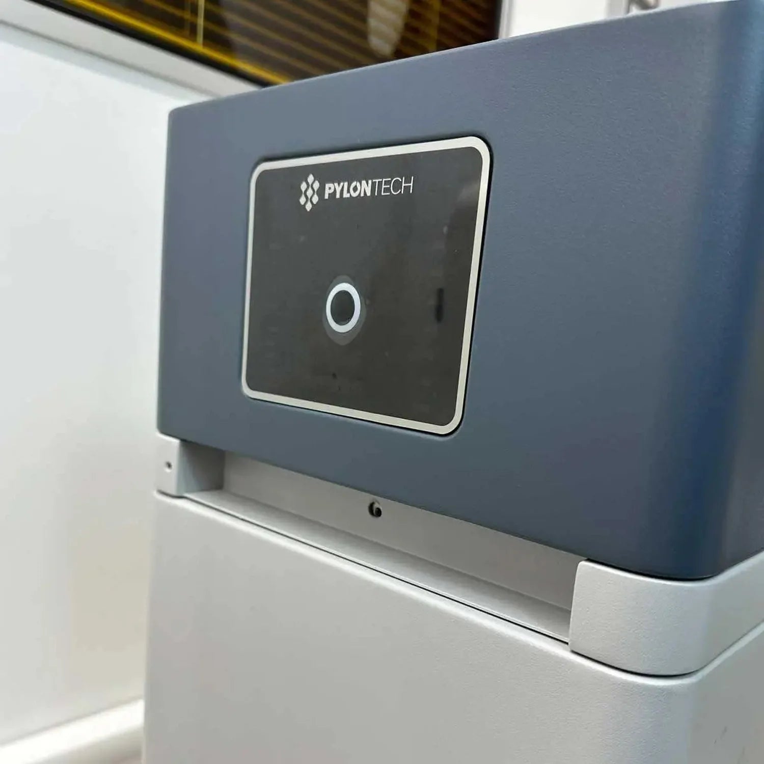 Pylontech Force controller mounted on white base, displaying zero on touchscreen display in industrial warehouse setting.