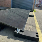 Solar panel mounting system installed on flat commercial roof with angled metal frame and rubber base blocks.