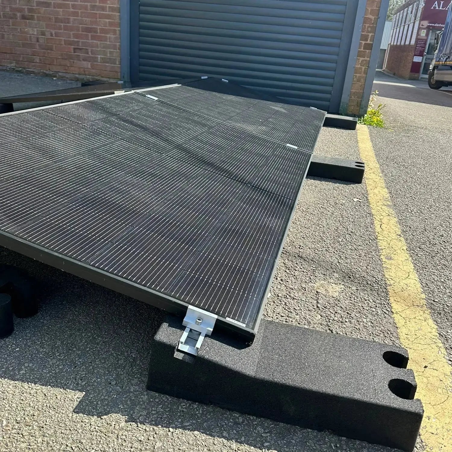 Solar panel mounting system installed on flat commercial roof with angled metal frame and rubber base blocks.