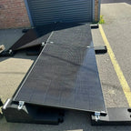 Flat roof solar mounting system with two panels installed on asphalt roof beside garage door, showing adjustable brackets and