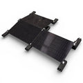 Black solar panel mounting system with multiple panels connected by hinges and supported by four corner brackets on white bac