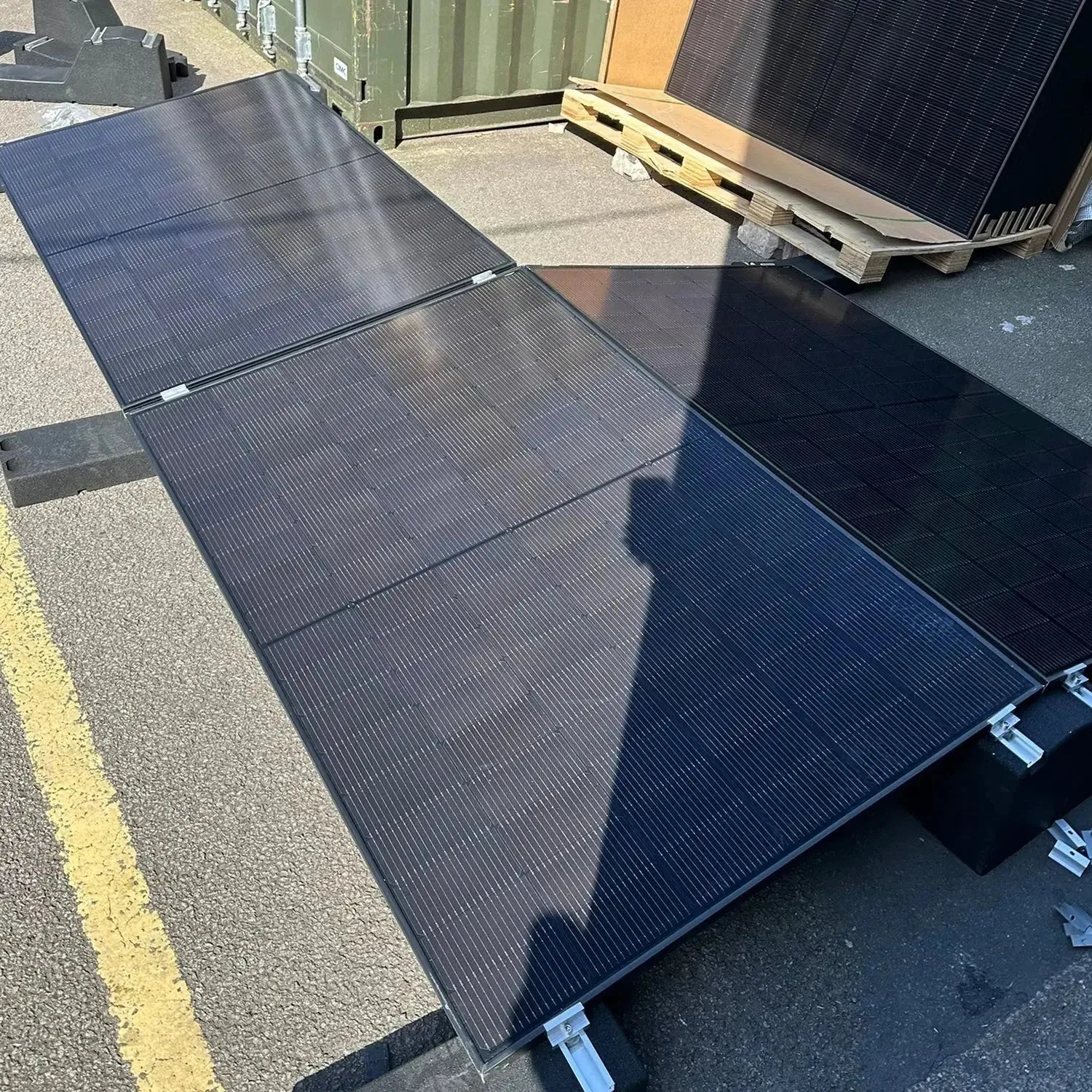 Multiple black solar panels mounted on flat roof system with east-west orientation, displayed outdoors in installation settin