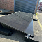 Solar panel mounting system installed on flat roof, angled eastward, with black aluminum frame and ribbed surface against bri