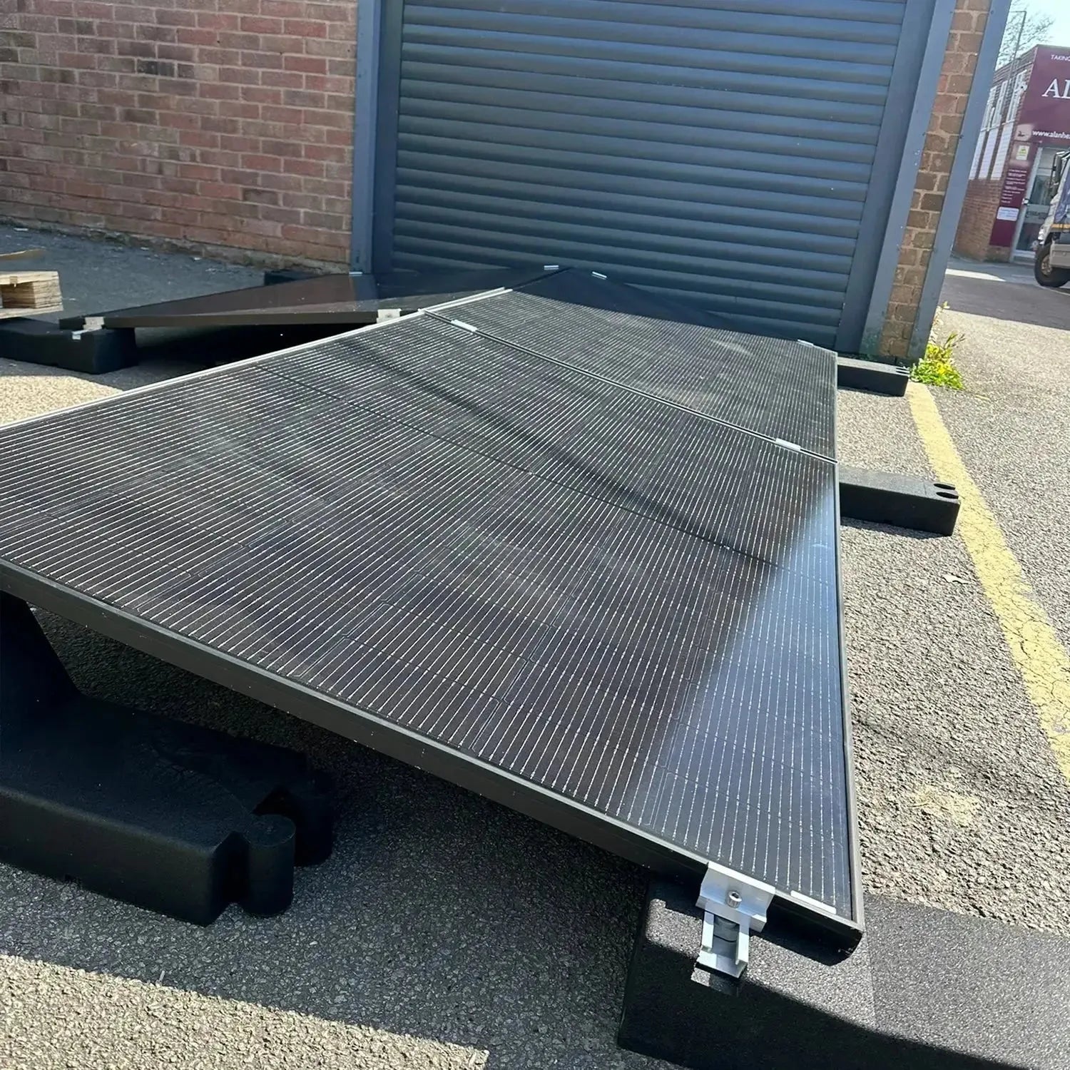 Solar panel mounting system installed on flat roof, angled eastward, with black aluminum frame and ribbed surface against bri