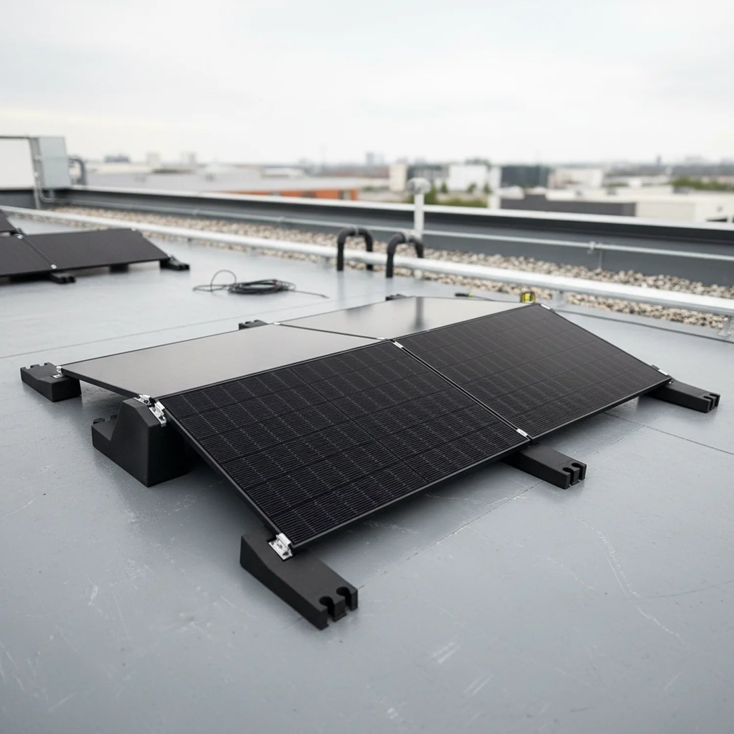 Flat roof solar mounting system with two black solar panels installed on industrial rooftop, industrial buildings visible in 