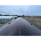 Gaia solar mounting system installed on flat agricultural roof with multiple panels and white polytunnels visible in backgrou