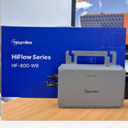Hoymiles HiFlow Series HF-800-WB micro inverter next to its blue packaging box, displayed on wood with solar panels visible i