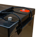 Black deep cycle battery with red terminal cap, mounted on brown surface with black rope handles and metal mounting brackets.
