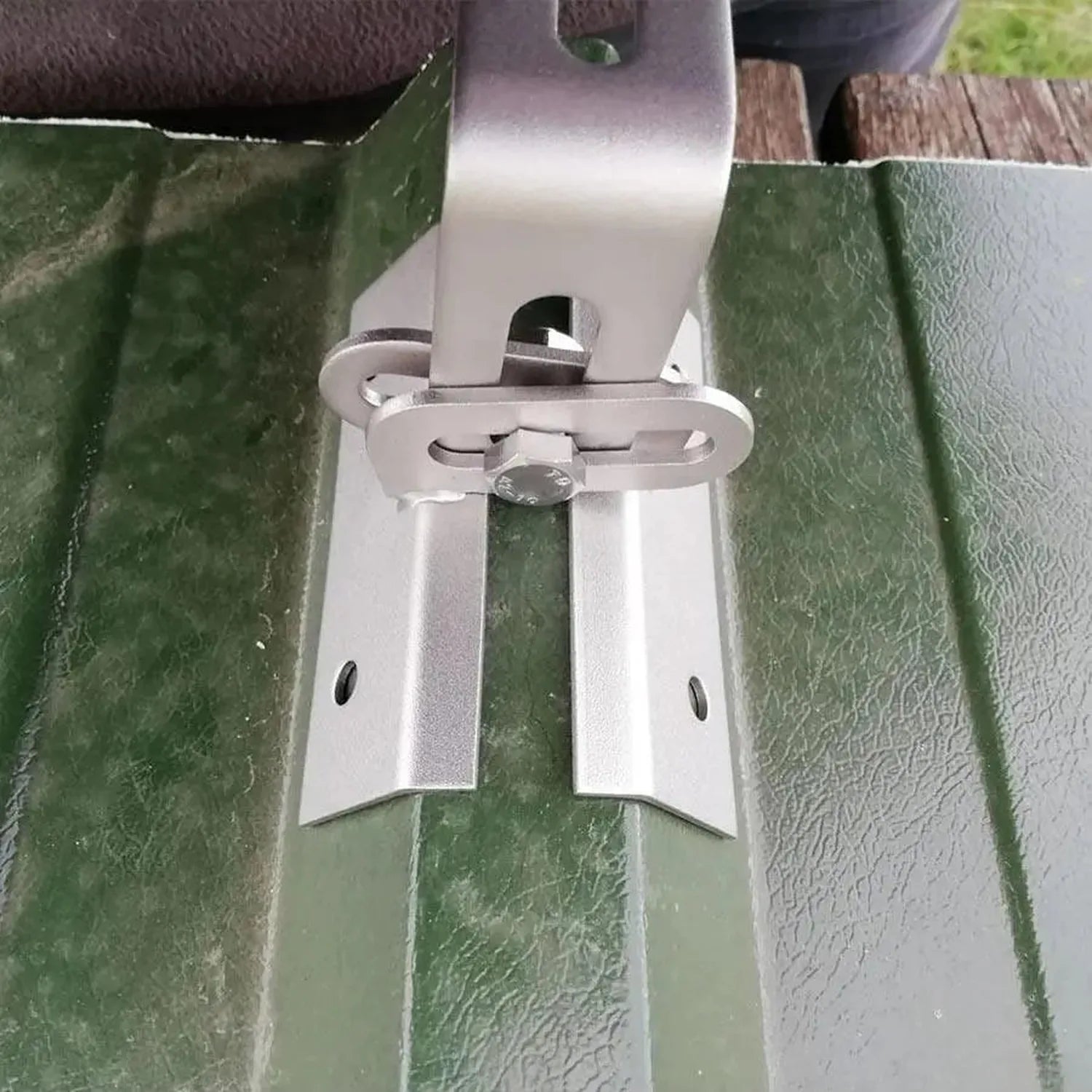 White adjustable solar panel mounting bracket installed on green trapezoidal metal roof panels with adjustment lever visible.