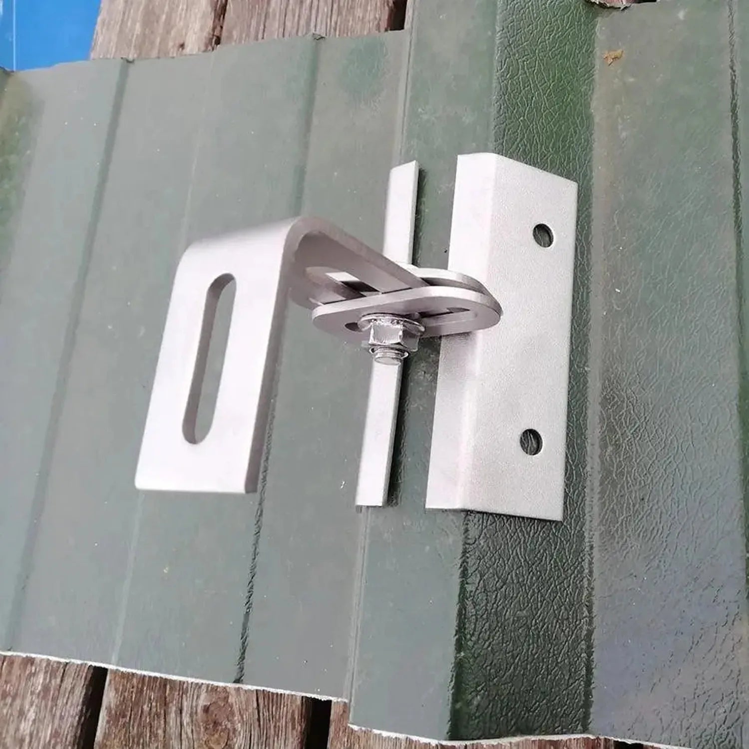 Adjustable solar panel mounting bracket installed on green trapezoidal metal roof panels with wing nut fastener visible.