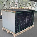 JA Solar 600W bifacial solar panel mounted on wooden pallet with green protective fencing, displayed indoors.
