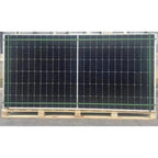 Pallet of 36 black bifacial solar panels with green aluminum frames stacked on wooden pallets.