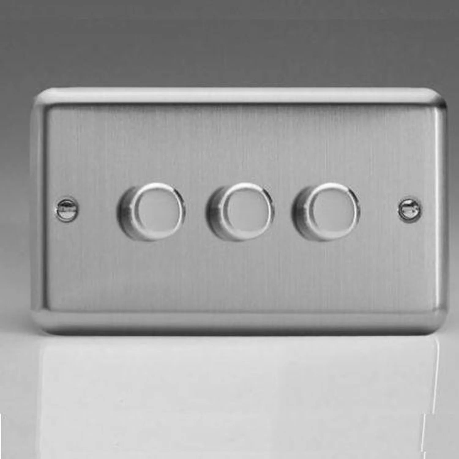 Brushed steel 3-gang dimmer switch with three rotary dials and mounting holes on left and right sides.
