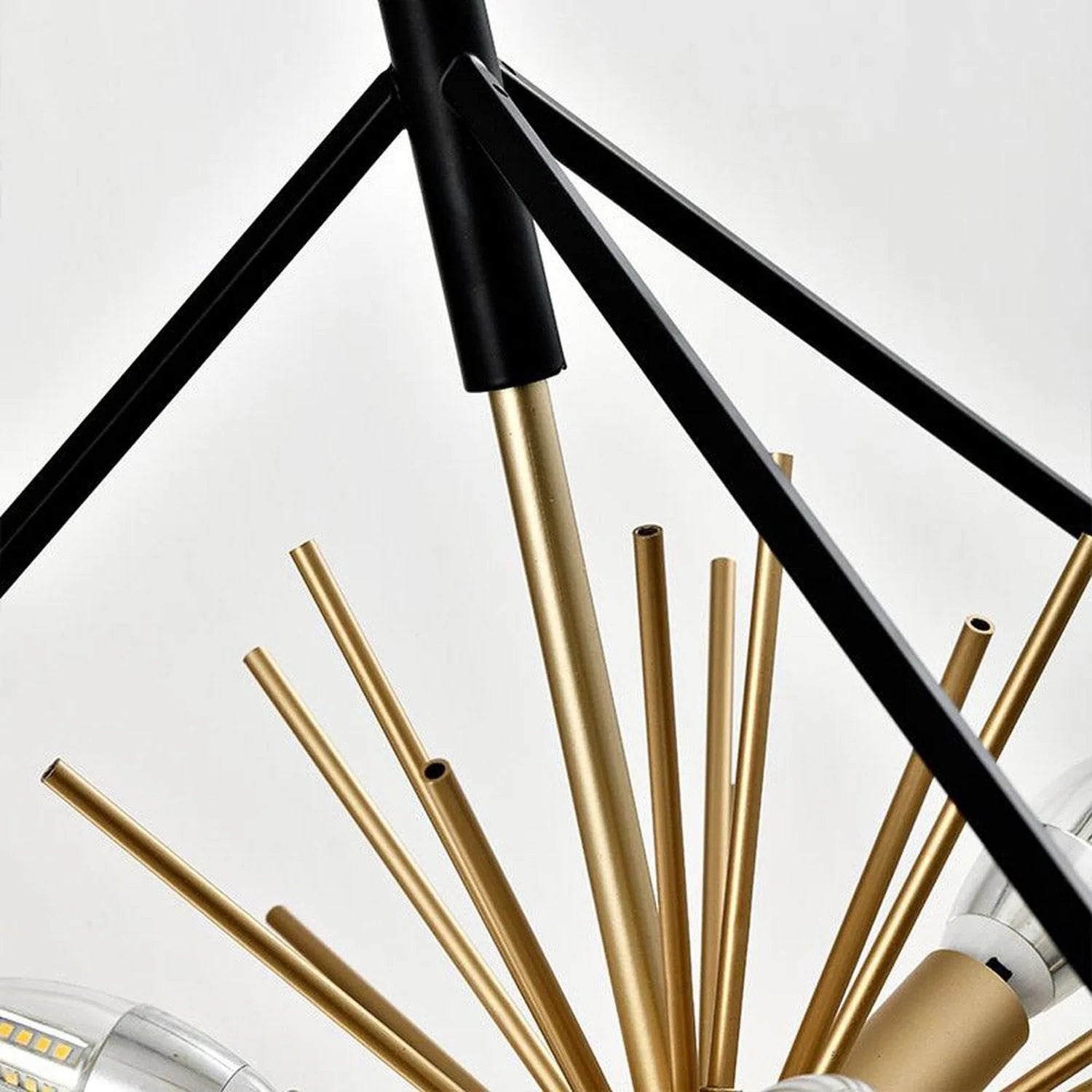 Astral LED ceiling pendant with black frame and multiple brass-colored candle-shaped arms arranged in a radial pattern agains