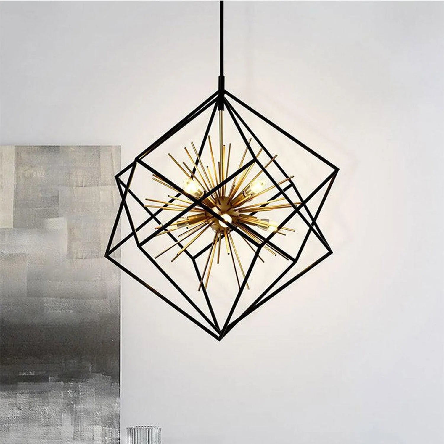Black geometric star pendant light with brass spikes and candle-style bulbs, hanging in modern interior space.