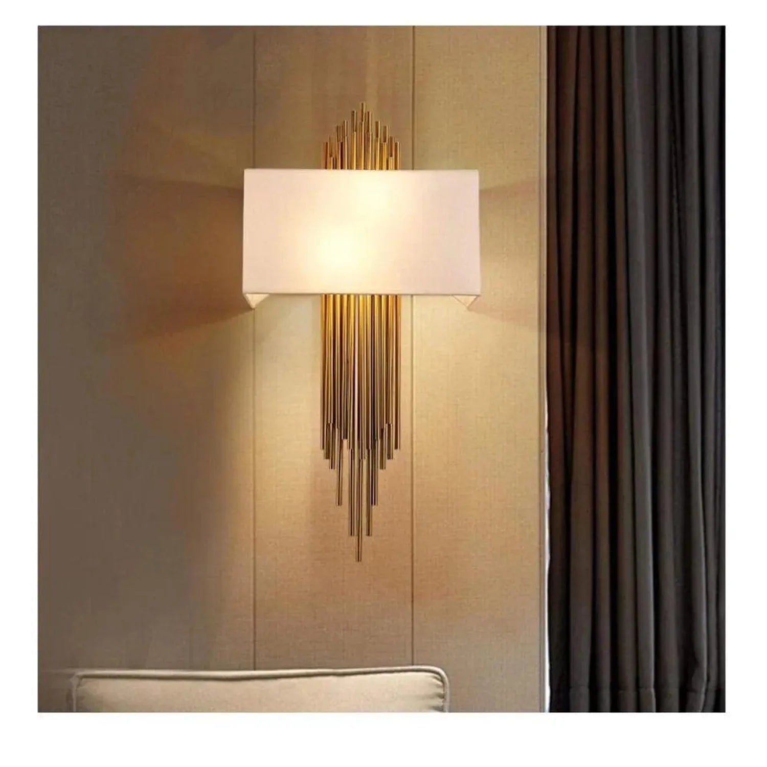 Modern gold wall sconce with rectangular cream shade and cascading metal rods, installed above upholstered headboard in warm 