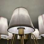 Aurelia Gold 8 Light Chandelier with white fabric drum shades and brass arms mounted on ceiling, installation shot.
