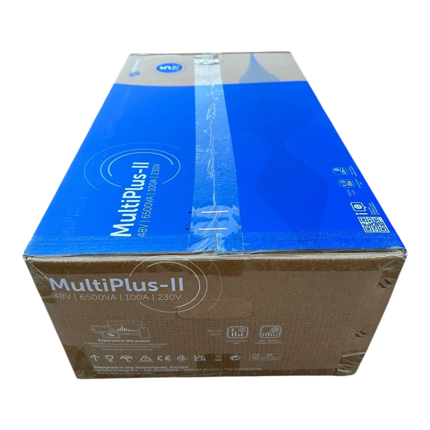 Cardboard shipping box for MultiPlus-II inverter charger, blue and tan packaging with specifications and CE markings visible.