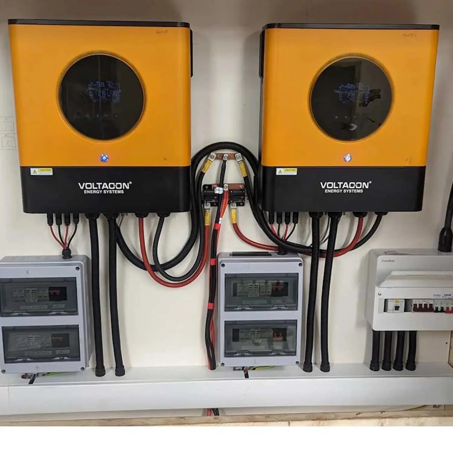 Two Voltacon Energy Systems inverters mounted on wall above monitoring equipment and electrical panels in solar installation 
