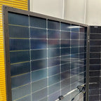 Large solar panel array display showing multiple photovoltaic modules mounted in showroom setting with yellow storage unit vi