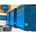Blue Victron Quattro inverter chargers mounted in an installation, showing multiple units with orange accent stripes and cont