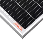 Close-up of 180W monocrystalline solar panel showing black cells in herringbone pattern, white aluminum frame, and orange man
