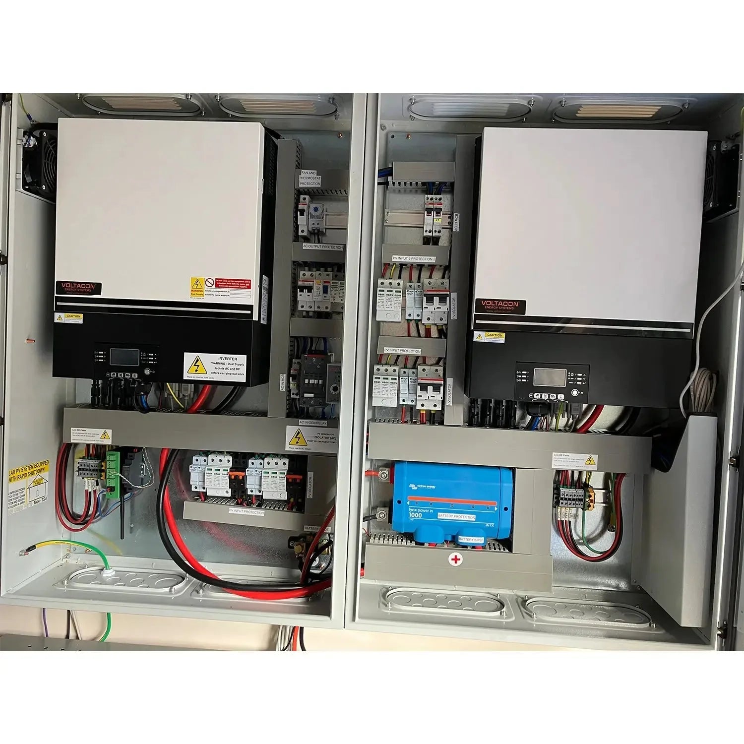 Two wall-mounted electrical cabinets with Voltacon inverters, circuit breakers, wiring, and a blue Victron charge controller 